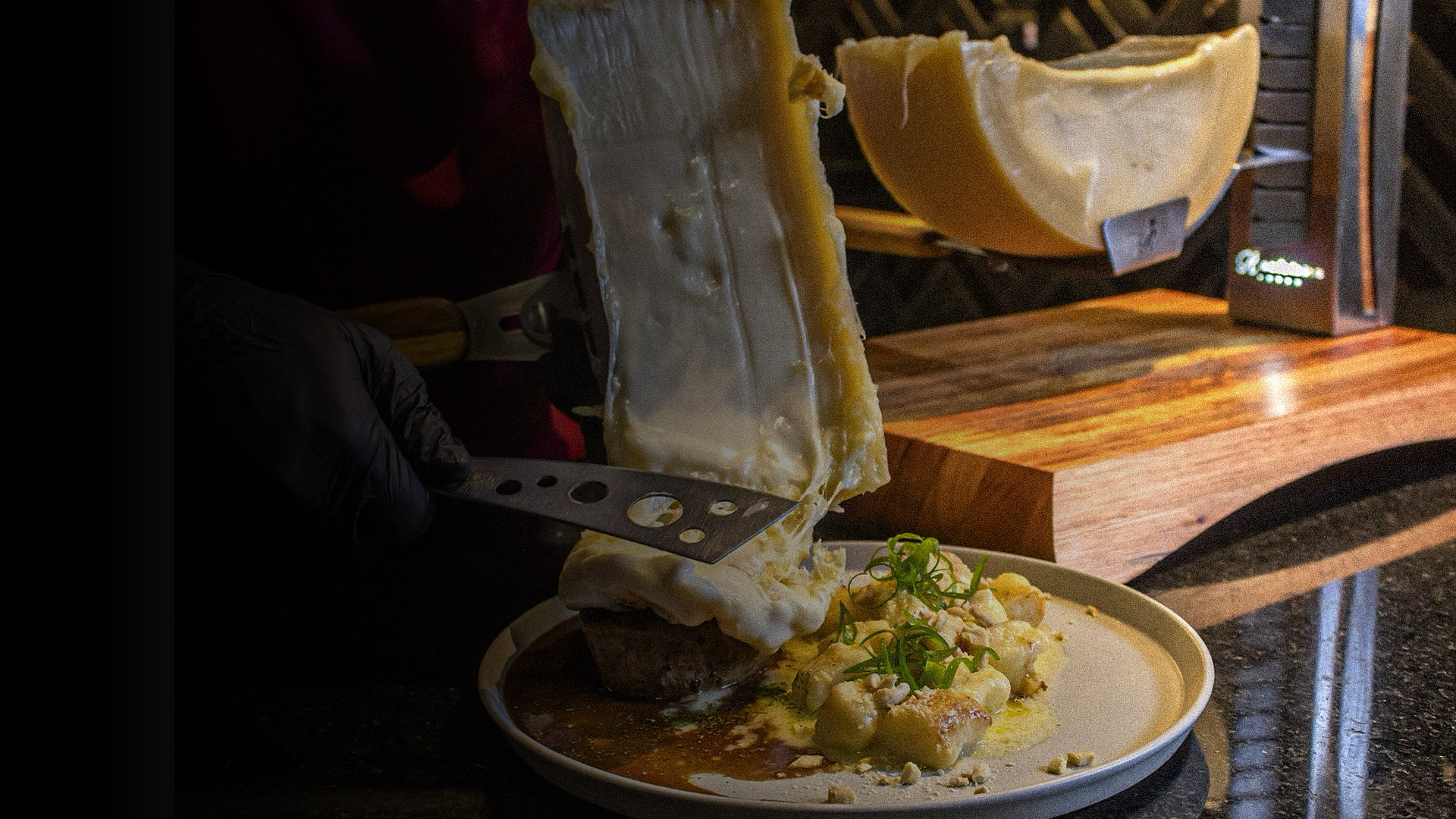 Raclette derretida sendo raspada sobre o prato no Ticino