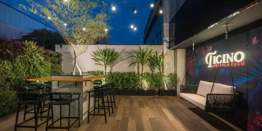 Terraço externo com balanço e o logotipo neon do Ticino